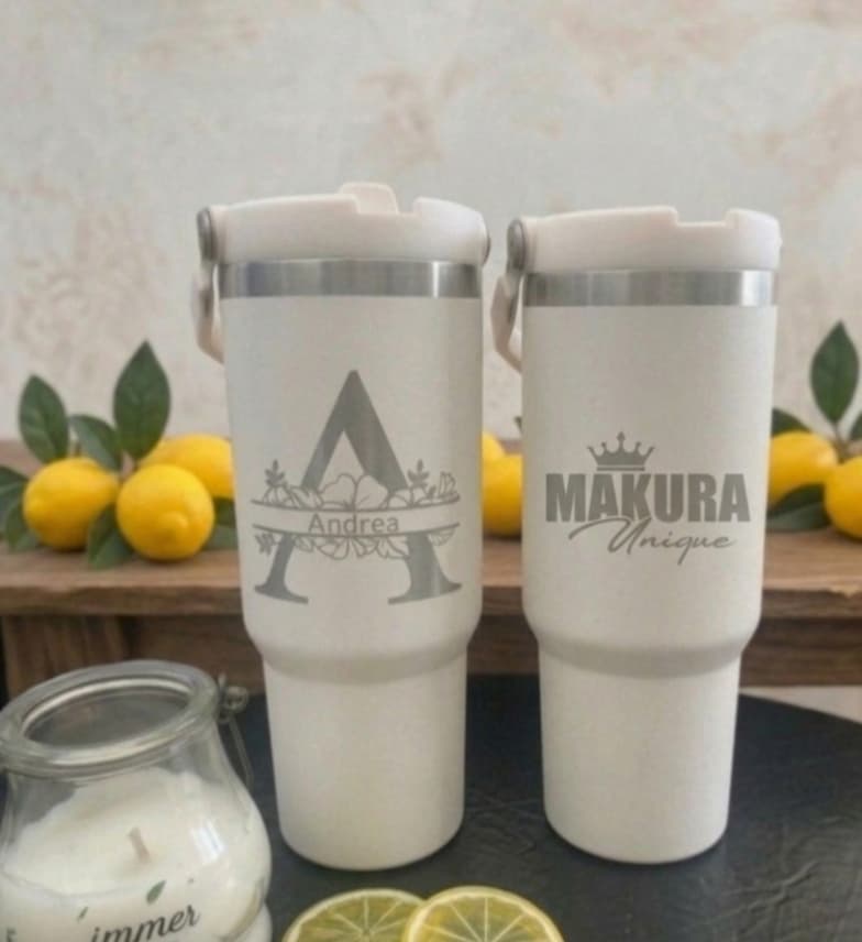Zwei gravierte Thermobecher, einer mit Monogramm „A“ und dem Namen Andrea, einer mit Makura-Unique-Logo